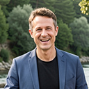 Bürgermeister Hannes Püdelhorst macht eine Erfrischungspause am Schalusen-Bach. Er lehnt an ein Fahrrad und hält ein Bier in der Hand. Neben ihm ein Grill mit Maiskolben. Im Hintergrund am Waldrand sonnt sich eine Person